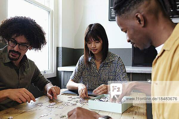 Multiracial business colleagues playing puzzle game at office