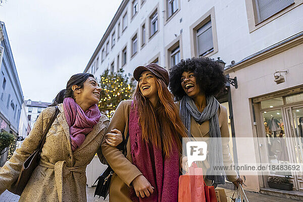 Happy multiracial friends walking with shopping bags in city