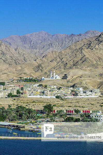 Buildings and seaport in front of mountains on sunny day