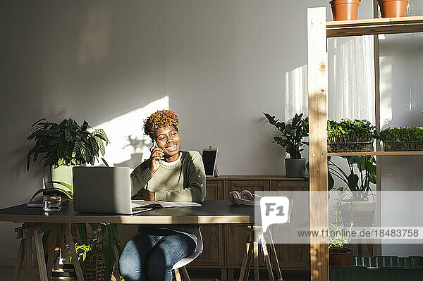 Glückliche Geschäftsfrau  die am Schreibtisch mit dem Smartphone spricht