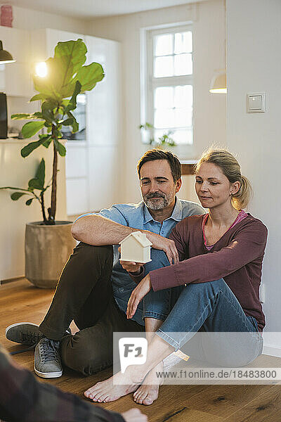 Man and woman with house model sitting on floor at home