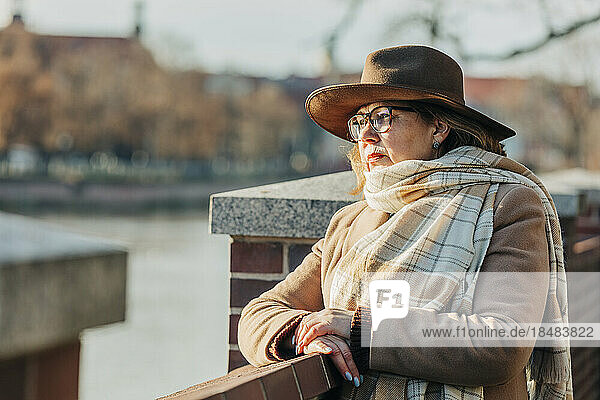 Thoughtful senior woman wearing scarf near railing