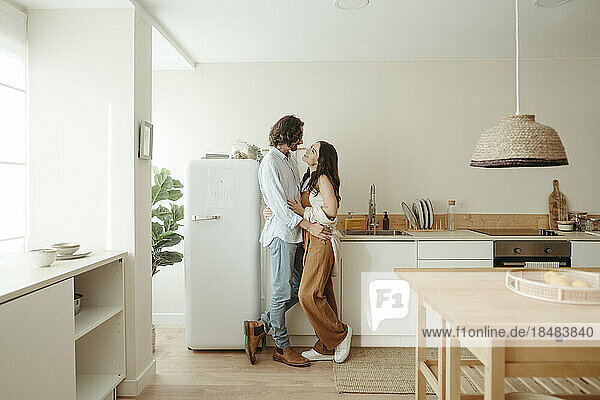 Happy couple standing together in kitchen at home