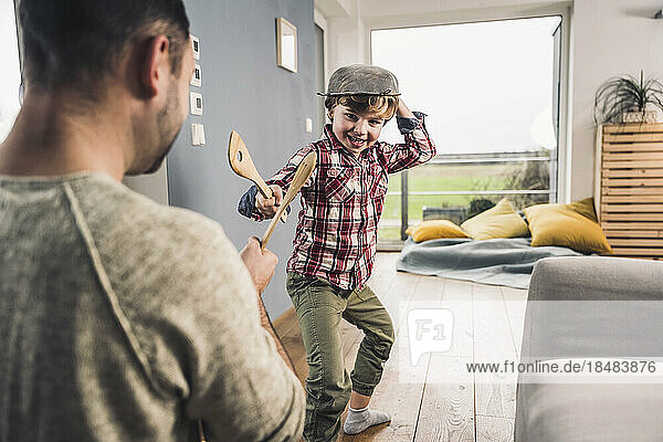 Father and son playing with spatulas at home