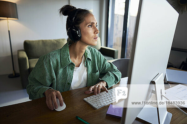 Freelancer wearing wireless headphones working on desktop PC