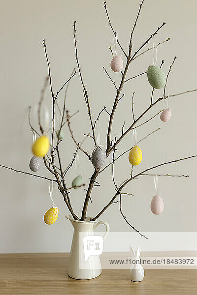 Easter eggs hanging on twigs in vase at home