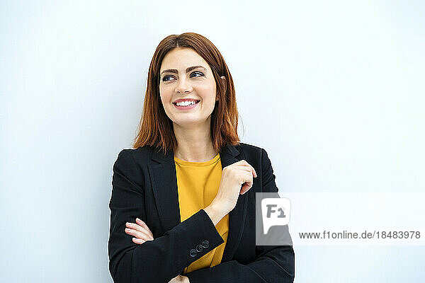Happy businesswoman with arms crossed against white background