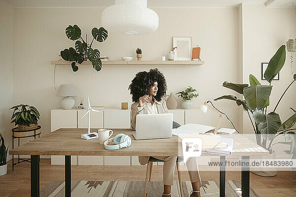 Thoughtful businesswoman with Afro hairstyle sitting in office