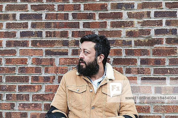 Thoughtful mature man in front of brick wall