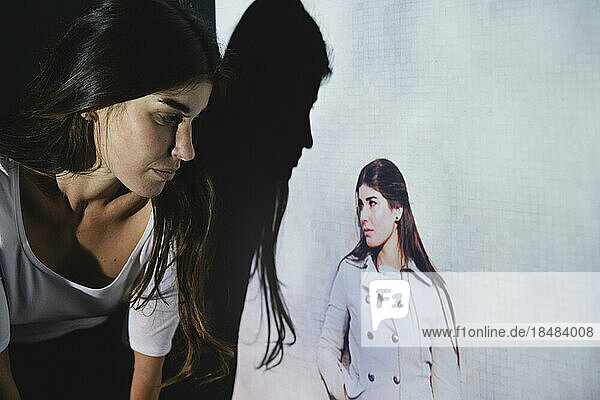Young woman looking at her photo on projection screen