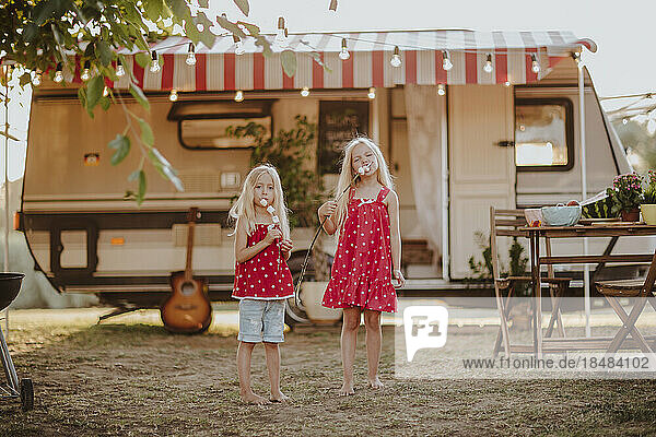 Sisters eating marshmallow in front of motor home
