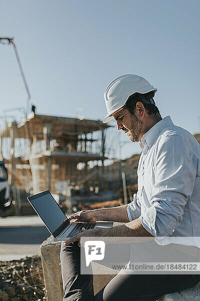 Architect working on laptop at construction site