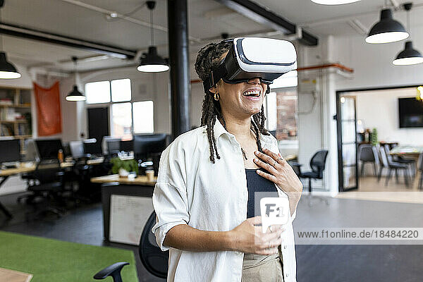 Happy businesswoman wearing VR glasses standing in office