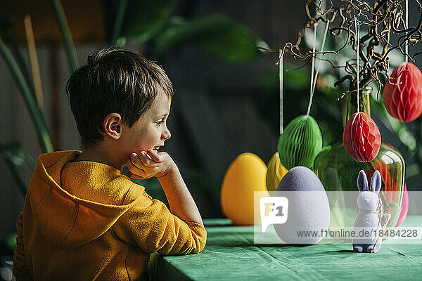 Smiling boy looking at Easter decoration on table at home