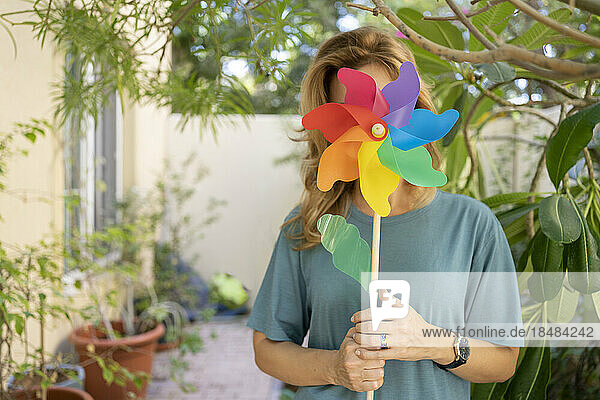 Woman holding pinwheel toy over her face