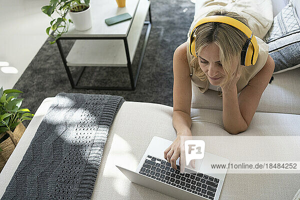 Freelancer wearing wireless headphones using laptop at home