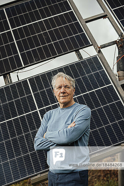 Smiling man with arms crossed standing in front of solar panels
