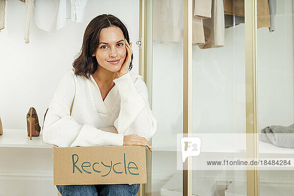 Smiling woman sitting with box of recycle at home