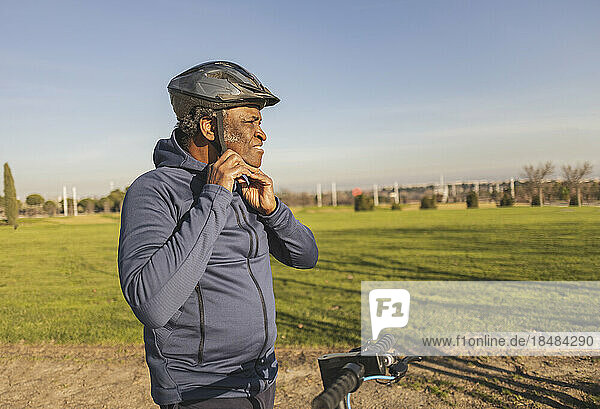 Contemplative senior man wearing helmet on sunny day