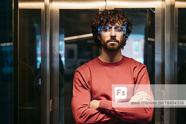 Young man with smart glasses and arms crossed in elevator