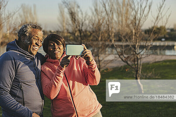 Happy senior woman sharing smart phone with man at park