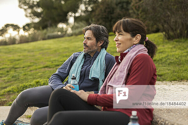 Thoughtful mature man and woman sitting in park
