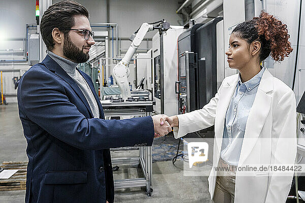 Smiling businessman shaking hands with colleague in industry