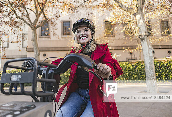 Glückliche reife Frau mit Helm  die auf der Straße Fahrrad fährt
