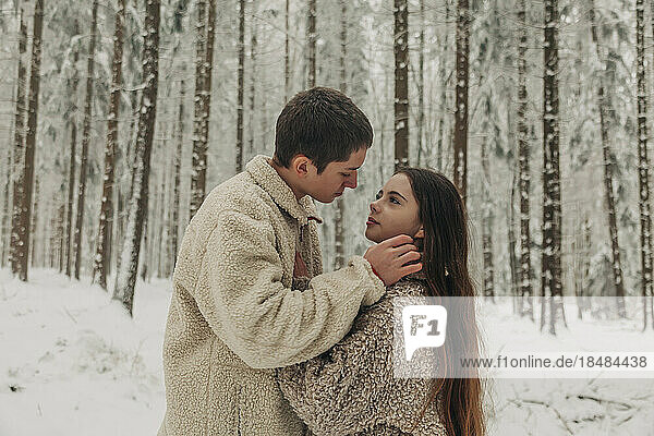 Romantisches Teenagerpaar steht zusammen im verschneiten Wald