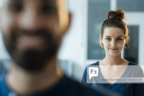 Lächelnde Geschäftsfrau steht mit Kollegin im Vordergrund im Heimbüro