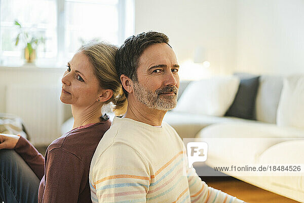 Mature man sitting back to back with wife at home