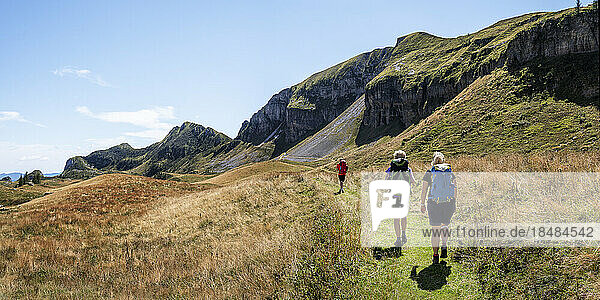 Women and man hiking towards Rifugio dal piaz on sunny day at Dolomites  Italy