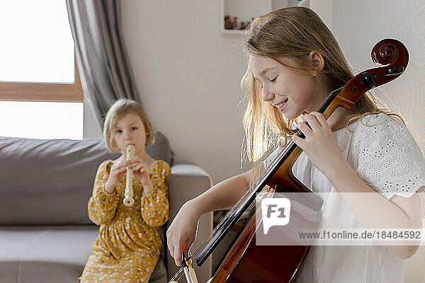 Happy girls playing musical instruments at home