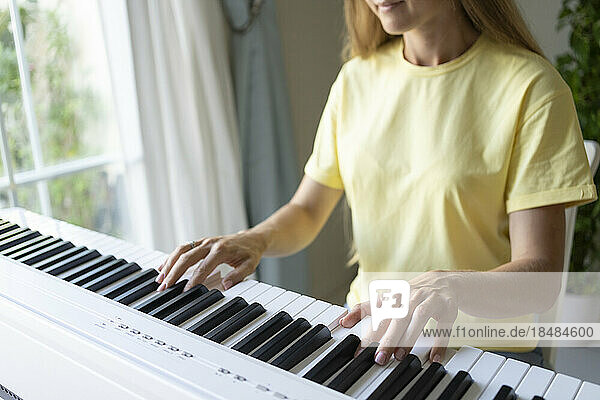 Hands of woman playing piano at home