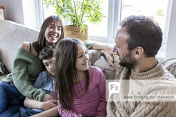 Happy woman sitting with family on sofa at home
