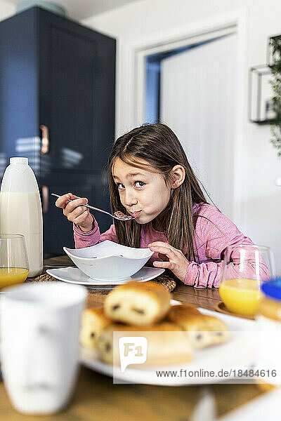 Smiling girl having breakfast at table