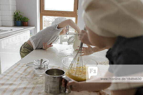 Junge nimmt Mehl  um zu Hause Teig zuzubereiten