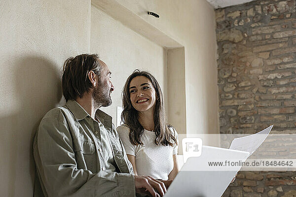 Happy woman and man sitting with laptop at home