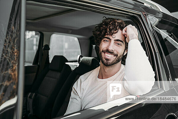 Happy young man with beard traveling in car