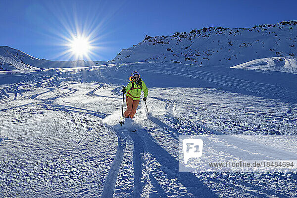 Österreich  Tirol  Die Sonne scheint über einer Skifahrerin  die den schneebedeckten Hang in den Tuxer Alpen hinunterrutscht