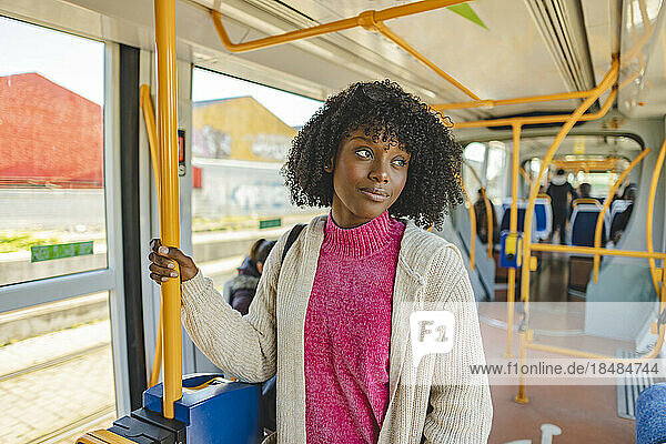 Smiling young woman with curly hair standing in tram