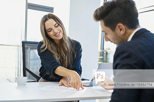 Recruiter assisting candidate filling form at desk in office