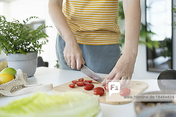 Woman cutting cherry tomatoes at home