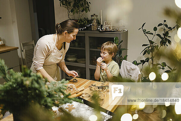Happy mother and son making Christmas cookies at home