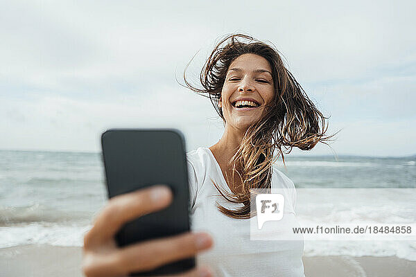 Fröhliche Frau  die am Strand ein Selfie mit ihrem Smartphone macht