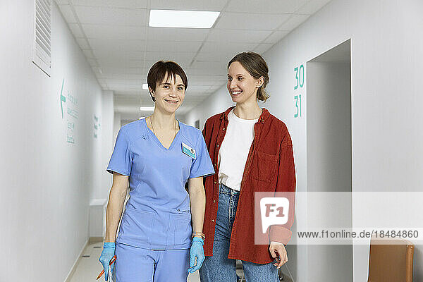 Smiling patient standing with doctor in corridor at hospital