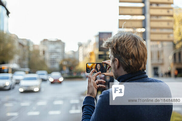 Man gesturing and talking to woman on video call at street