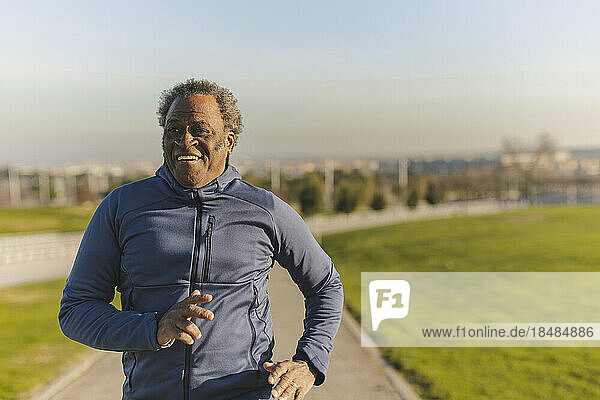 Happy senior man jogging on sunny day