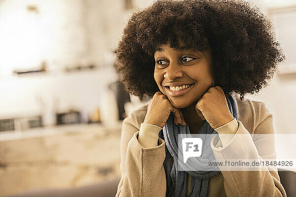 Glückliche junge Frau mit Afro-Frisur sitzt im Café