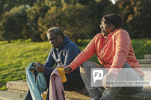 Älteres Paar mit Energy-Drink sitzt im Park
